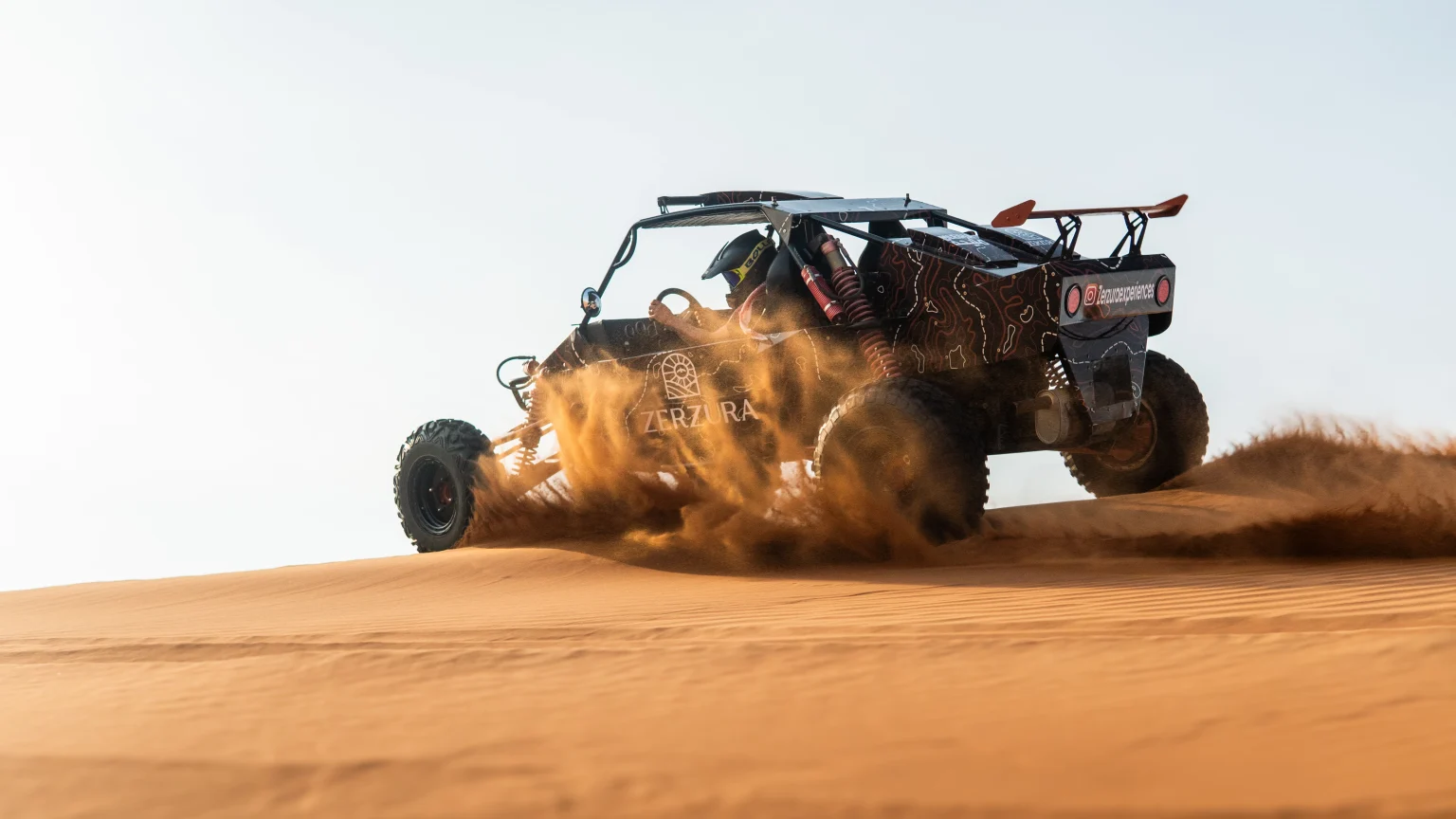 Affluent traveler driving a self-drive dune buggy across Dubai desert dunes during luxury safari