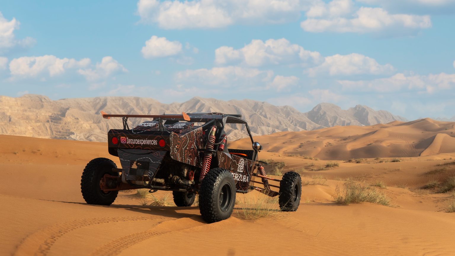 Dune buggy kicking up sand during a high-speed desert safari Dubai experience with Zerzura in Mleiha